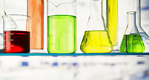 Photo of 6 colorful solutions on a lab table.