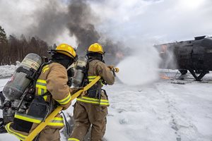 Two Firefighters hold on tight to a spraying hose as they try to put out a fire