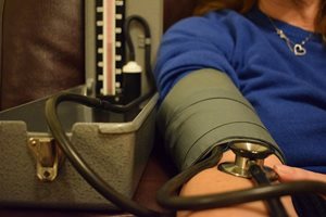 A photo of a person's upper arm with a sphygmomanometer and a stethoscope