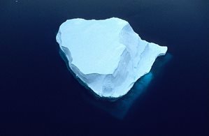 Iceberg floating on the water with some of the underwater part visible through the water.
